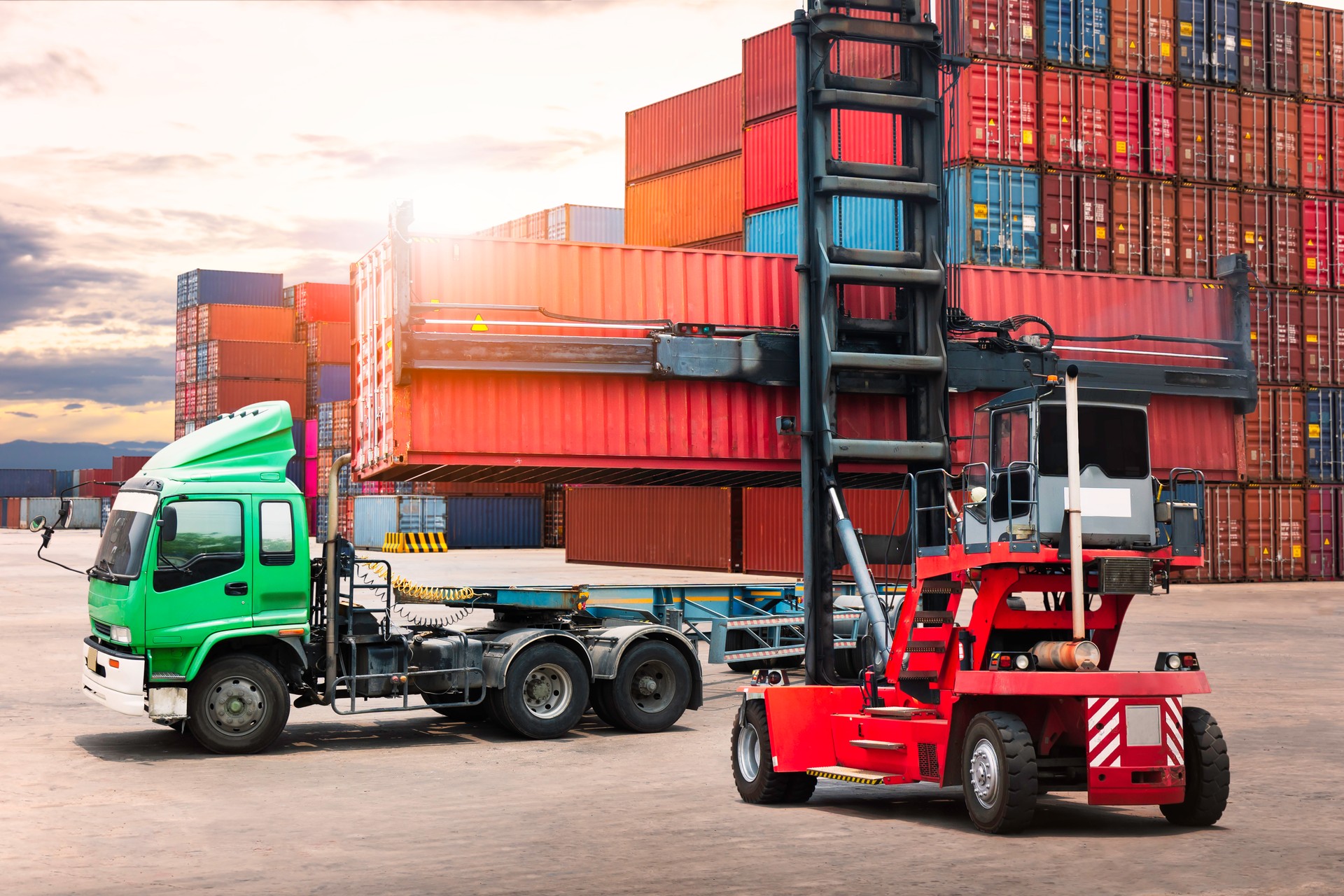 Container Crane Tractor Lifting up Container Box on Trailer Truck. Handling of Logistics Transportation Industry. Cargo Container ships, Freight Trucks Import-Export. Distribution Warehouse Shipping.